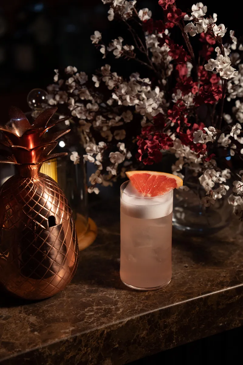 Grapefruit cocktail beside a copper pineapple and blossom