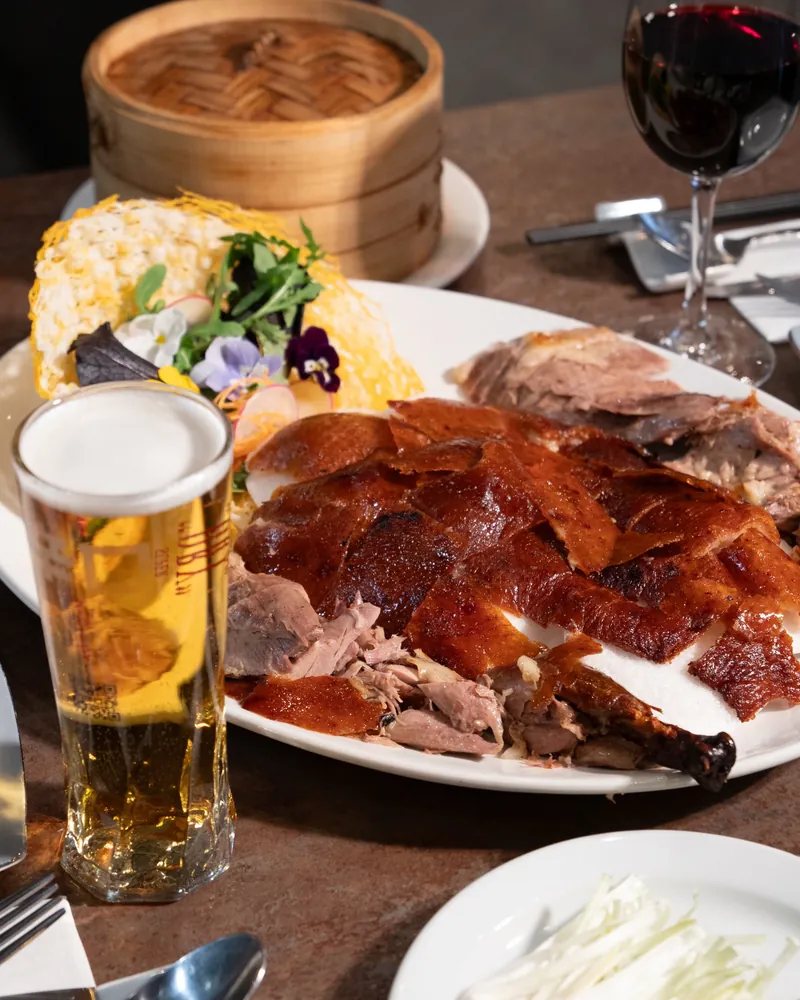 Peking duck carved on a platter with a glass of beer