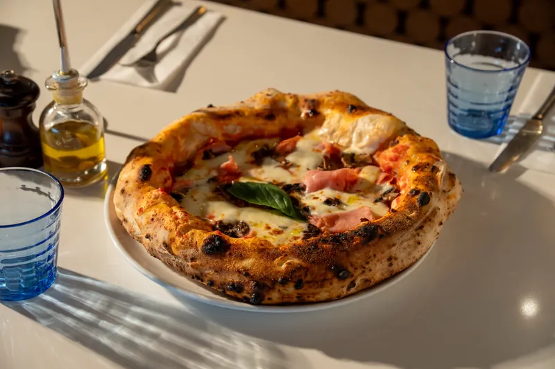 Wood-fired pizza with ham, mushroom and basil